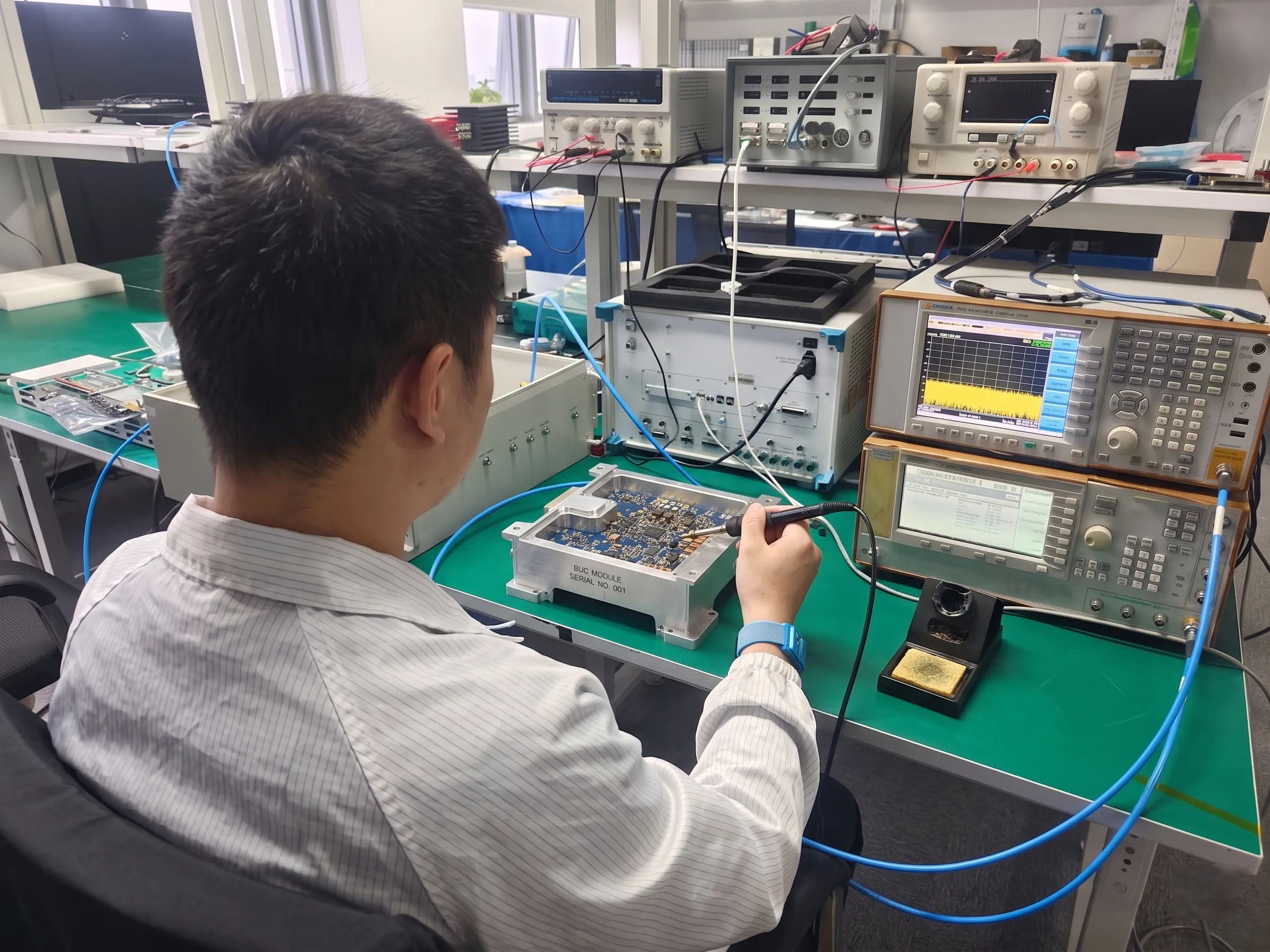 Technician adjusting a BUC with an attenuator on the workbench